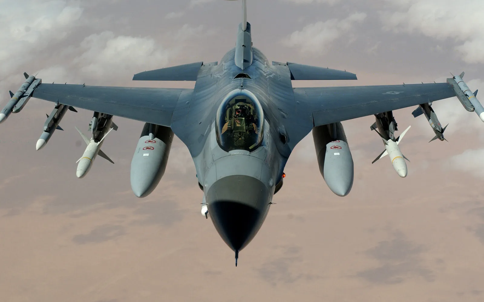 An F-16 Fighting Falcon fighter jet in flight over ocean waters